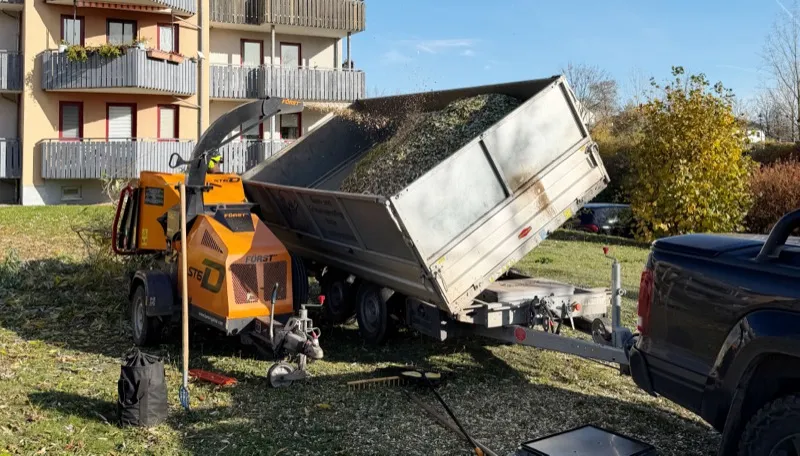 Mobiler Häcksler kippt Hackschnitzel auf Anhänger beim Häckseldienst