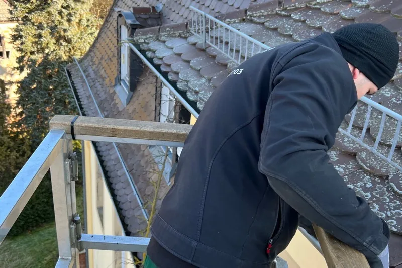 Mitarbeiter der Baum- und Grünanlagenpflege Ritter bei der Dachrinnenreinigung vom Gerüst